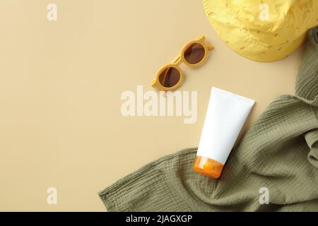Flat lay sunscreen cream for babies with sunglasses, towel, panama hat on beige table. Kids skin sun protection concept Stock Photo
