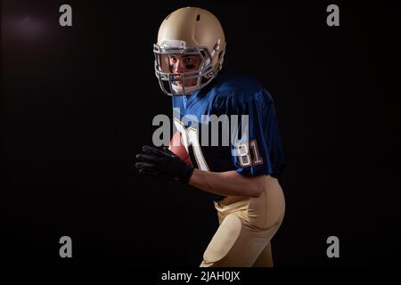 Young football player in running action on a dark background Stock Photo