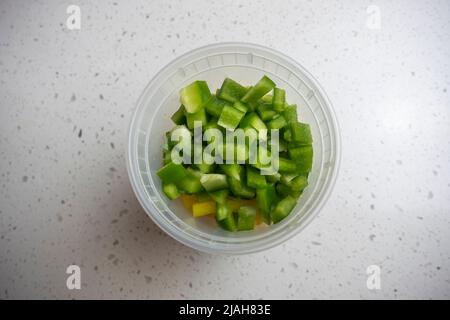 View of coloful diced bell peppers in a plastic container on a kitchen counter, prepped for cooking Stock Photo