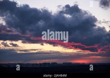 A large dark cloud with a glimmer of light from the red setting sun Stock Photo