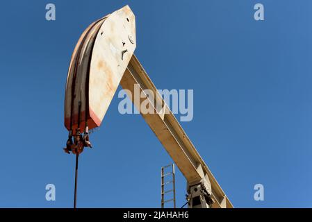 Closeup of a pumpjack in an oil field agaist a bright blue sky. Stock Photo