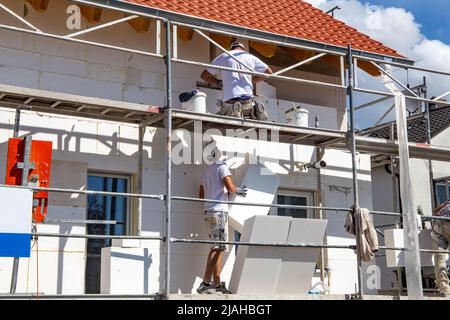 Construction workers insulates house facade Stock Photo