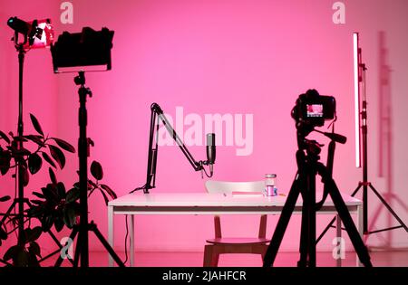 Horizontal no people interior shot of modern influencers studio equipped with camera, microphone and lighting devices, pink neon light Stock Photo