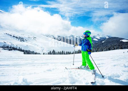 Boy stand on ski track in sport outfit observing the mountain Stock Photo