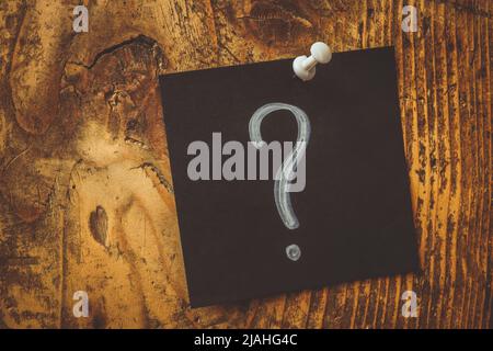 Pinned dark sticker and question mark on it. Stock Photo