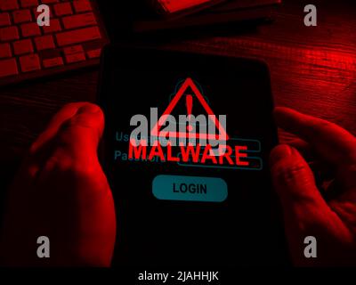 Hands in the dark hold a tablet with an inscription malware. Stock Photo