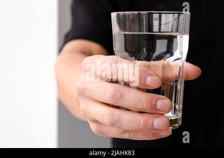 A glass with clean melted water in the hand of a man Stock Photo