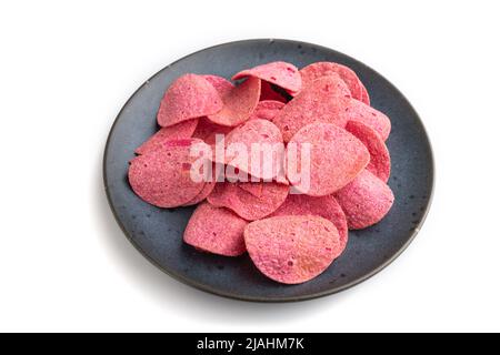 red potato chips with herbs and tomatoes on blue cearmic plate isolated on white background. Side view, close up. Stock Photo