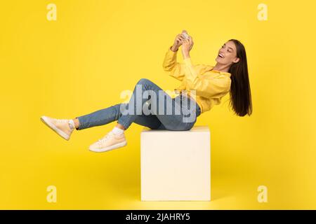 Happy young woman using cell phone at studio Stock Photo