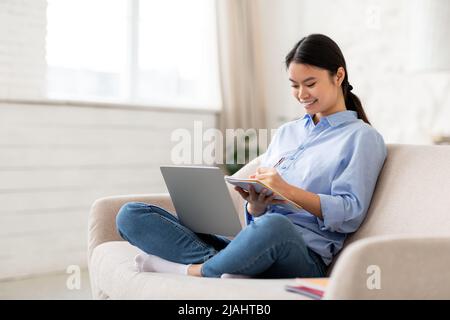 Happy asian woman student attending webinar, using laptop Stock Photo