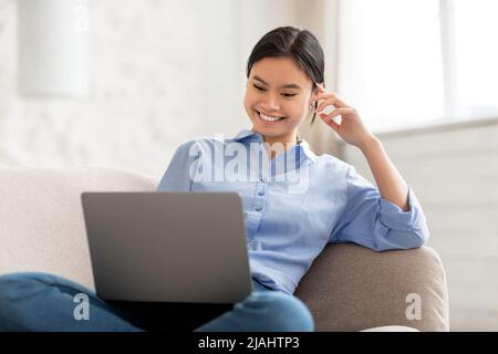 Cheerful korean woman chilling at home, using computer Stock Photo