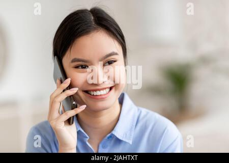 Closeup of smiling asian woman talking on cell phone Stock Photo