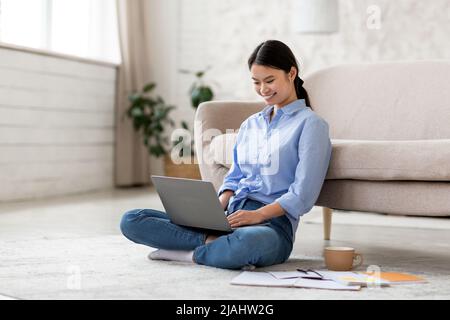 Cheerful korean lady working on project at home Stock Photo