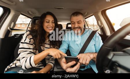 Happy couple driving car and using cell phone Stock Photo
