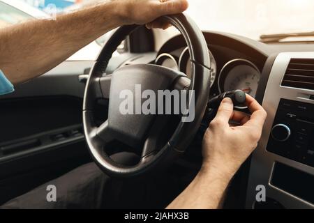 Man driving new car in city, turning on windshield wipers Stock Photo