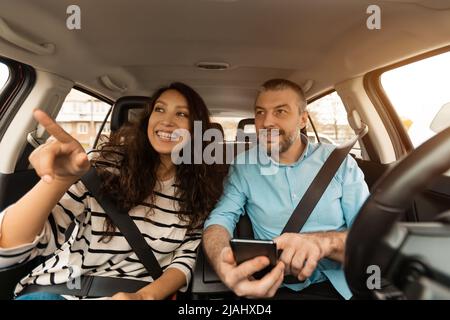 Happy couple driving car and using cell phone Stock Photo