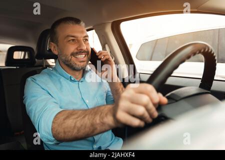 Happy man talking on smartphone while driving car Stock Photo
