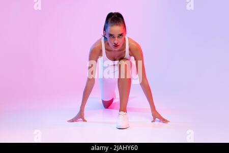 Runner Lady Posing Doing Crouch Start On Pink Background Stock Photo