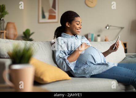Cheerful Pregnant African Lady Using Smartphone Video Calling At Home Stock Photo