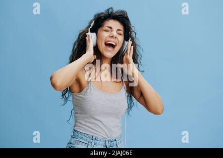 MUSIC STREAMING PLATFORM AD CONCEPT. Enjoyed beautiful Latin female touch headphones, sing, scream. Cool offer for Phone pc fashion brands karaoke ad Stock Photo