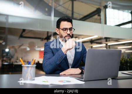 Smart pensive handsome young middle eastern businessman with beard in glasses Stock Photo