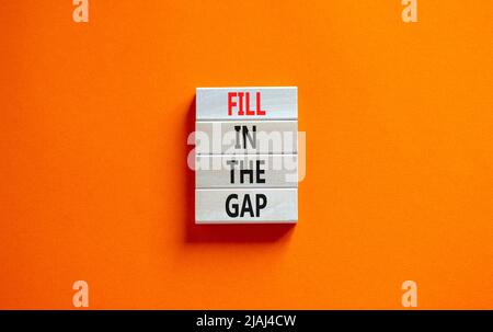 Fill in the gap symbol. Concept words Fill in the gap on wooden blocks on a beautiful orange table orange background. Business, motivational and fill Stock Photo