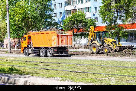 Samara, Russia - May 26, 2022: Dump truck Kamaz and front loader are working on the improvement of city streets in summer Stock Photo