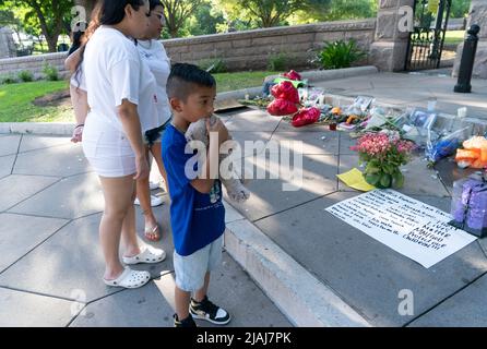 Austin Texas USA, May 30 2022: Little boy hugs a stuffed animal as he and his family look at photographs of many victims of the Uvalde, Texas mass murder at Robb Elementary, along with remembrance candles and bouquets of flowers at a makeshift memorial at the steps to the Texas Capitol grounds. Credit: Bob Daemmrich/Alamy Live News Stock Photo