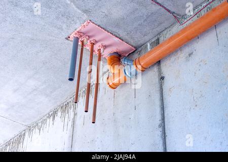 installation of water and sewer pipes in the technological opening of the interfloor overlap of the basement floor, selective focus Stock Photo