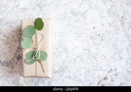 Gift box wrapped in brown paper decorated with eucalyptus branch, natural eco friendly zero waste gift wrapping idea. Top view. Copy space. Stock Photo