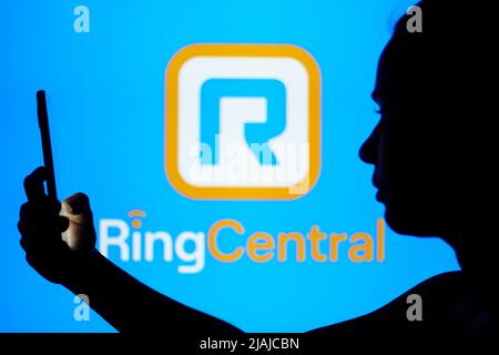 In this photo illustration, the RingCentral, Inc. logo is seen in the  background of a silhouetted woman holding a mobile phone Stock Photo - Alamy