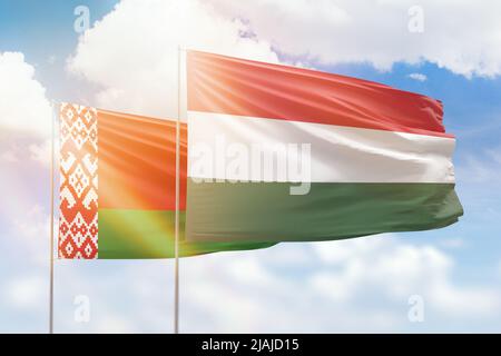 Belarus and Hungary flags waving together in the wind on blue cloudy ...