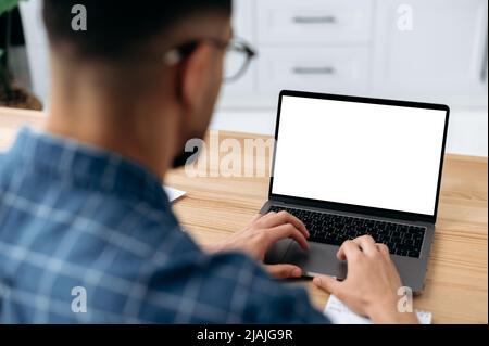 Laptop with white blank screen stand on a desk, male hands typing on the keyboard, browsing internet, information. Wireless technology concept. Mock-up concept for advertising and presentation Stock Photo