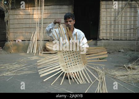 For the rest of the days he is a farmer. But every Sunday he goes to the market to buy bamboo sticks out of which he makes baskets to sell in the weekly market for an extra income. Kathiadi, Kishorganj. Stock Photo