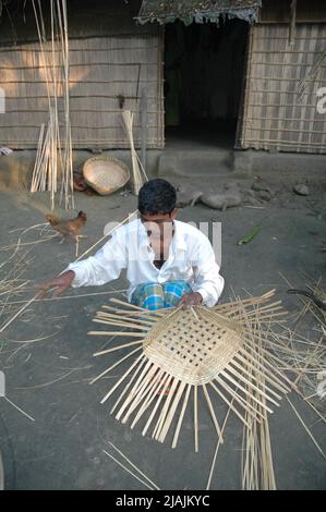 For the rest of the days he is a farmer. But every Sunday he goes to the market to buy bamboo sticks out of which he makes baskets to sell in the weekly market for an extra income. Kathiadi, Kishorganj. Stock Photo