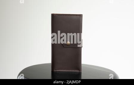 Man's handmade genuine leather wallet for banknotes and credit cards on a black surface with white background. Style, retro, fashion, vintage and Stock Photo