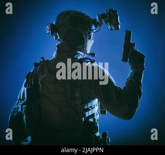 Low key studio shot of a special forces soldier on secret night mission with pistol in hand. Stock Photo