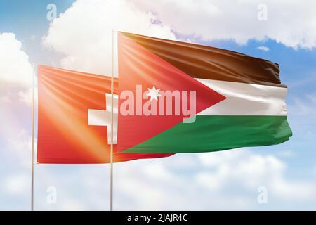 Sunny blue sky and flags of jordan and switzerland Stock Photo
