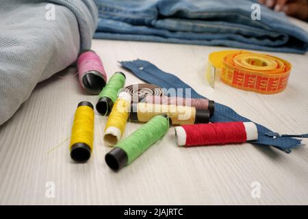 background with work table with colored threads, zipper, fabric and tape measure, sewing workshop with instruments, detail of objects in studio, hobbi Stock Photo
