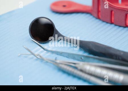 tweezers and sterile dental mirror on work table, ready-to-use medical tools in office, metal objects, medicine background Stock Photo