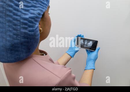 showing x-ray examination results on mobile device of a person's mouth, examining for dental treatment, technology and device in studio Stock Photo
