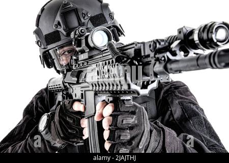 SWAT team member aiming assault rifle while observing territoy. Stock Photo
