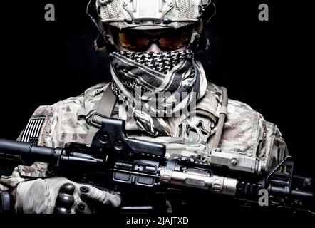 Modern combatant armed with rifle and face hidden behind shemagh, looking at camera. Stock Photo