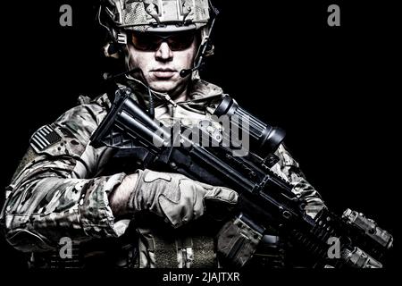 U.S. soldier armed with assault rifle, studio portrait on black background. Stock Photo