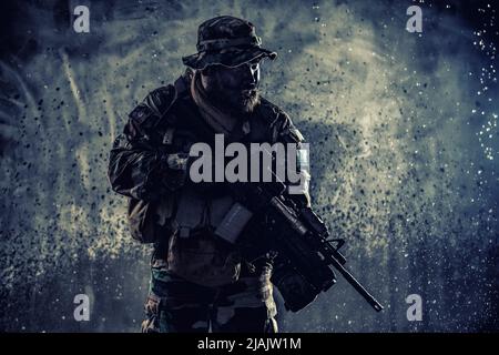 Commando fighter with assault rifle, sneaking in the darkness ready to ...