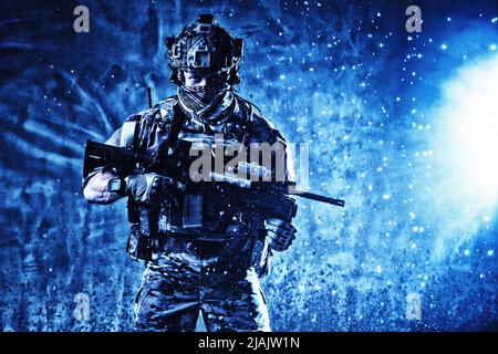 Soldier standing with assault rifle, looking at camera, surrounded by sparkles from an explosion. Stock Photo