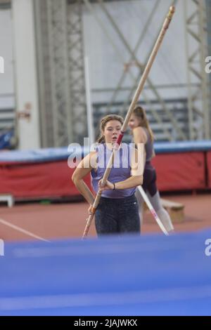 Pole vaulting indoors - young sportive woman with pigtails running with a pole in the hands Stock Photo