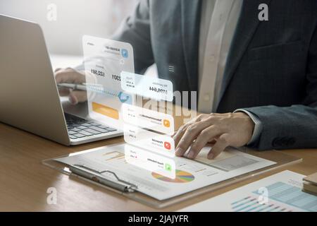 Businessman in front of computer notebook interacting with futuristic augmented reality screen while analysing a return on investment Stock Photo