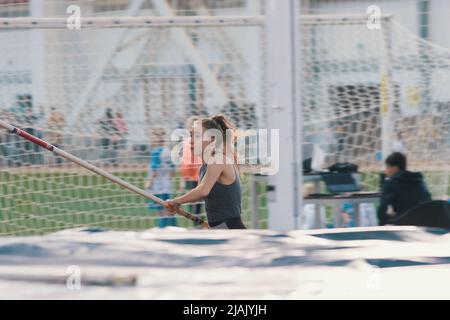 Pole vaulting indoors - young sportive woman with ponytail running with a pole in her hands Stock Photo