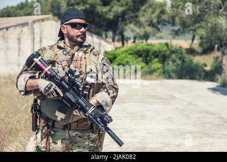 Half-length portrait of an armed Navy SEALs fighter wearing ballistic goggles while standing outdoors. Stock Photo